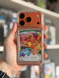A hand holding a clear phone case with a built-in card slot displaying a Charmander Pokémon card, set against a blurred indoor background.
