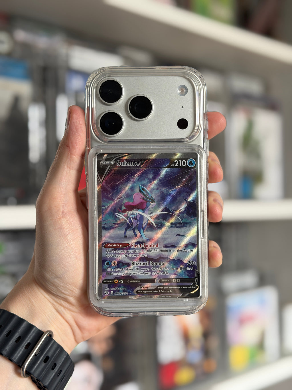 Transparent TCGCase phone case held in hand displaying Suicune V Pokémon card, front view